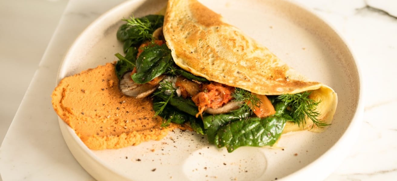 An omelette filled with greens on a ceramic dish.